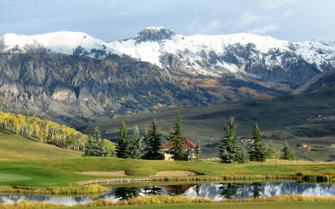 land and a pond with mountains in the background